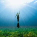 a woman standing in the middle of a grassy field